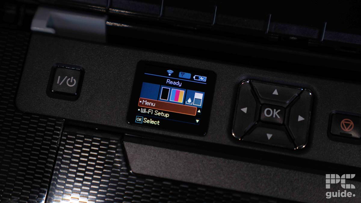 Close-up of an Epson WorkForce WF-110 control panel with an illuminated color screen displaying the menu, navigation buttons, and a visible power button. This compact printer promises versatility despite its slow printing speed.